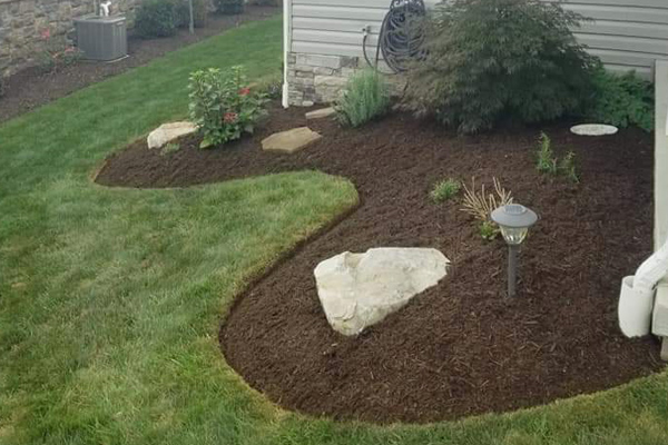 Our company created a new landscape bed with dark mulch and several new plants in front of a home.